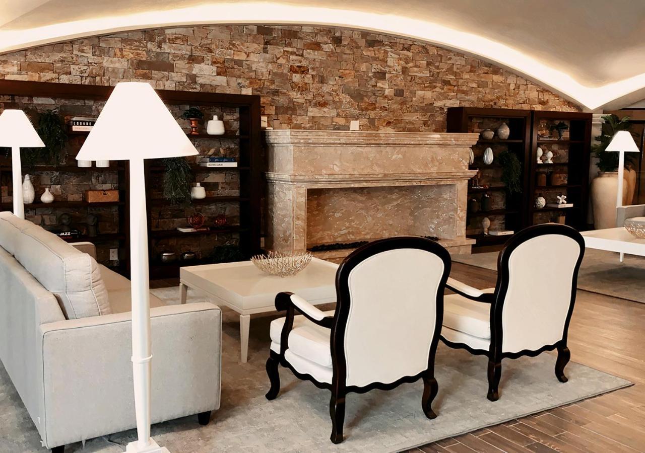 Hotel Buona Vitta Gramado by Gramado Parks Esterno foto The photo shows a stylish living room with a modern design. In the center, there is a light-colored sofa and two elegant white armchairs with black wooden frames. A coffee table is placed in front of the sofa. Behind them, there is a large, decorativ
