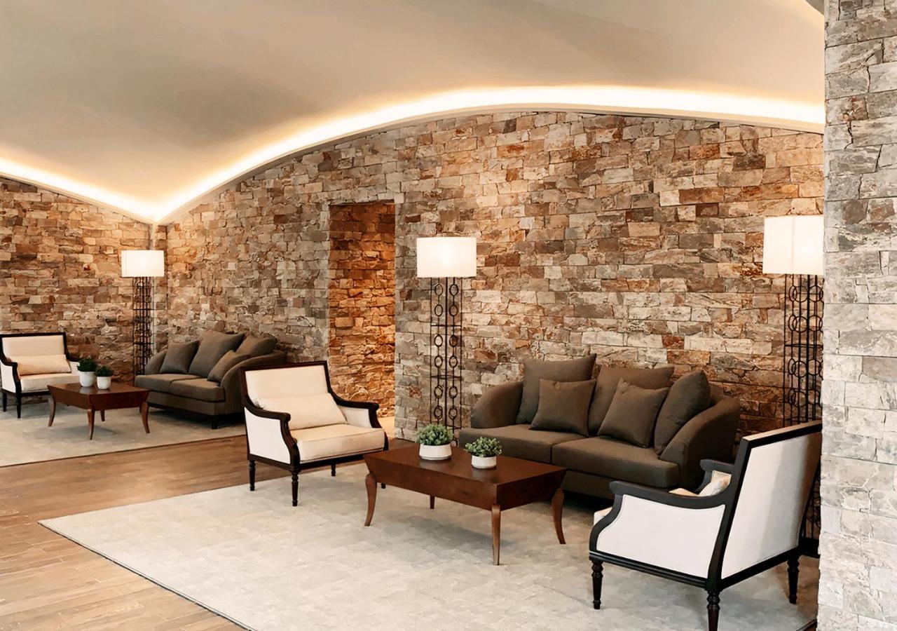 Hotel Buona Vitta Gramado by Gramado Parks Esterno foto The photo shows a stylish and modern lounge area. The walls are made of natural stone, creating a warm and inviting atmosphere. There are two comfortable sofas in a muted gray color arranged around a wooden coffee table. Flanking the sofas are elegan