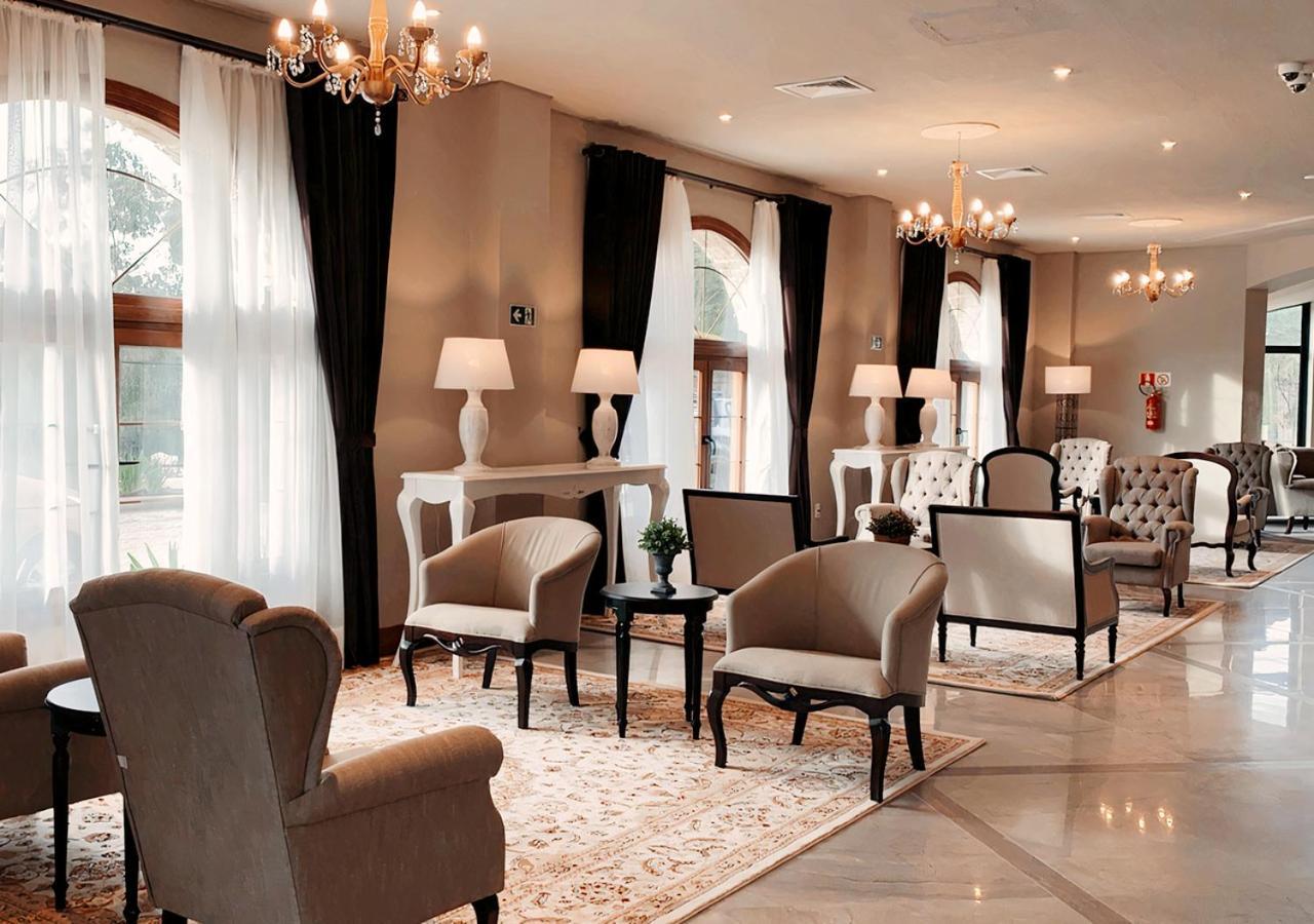 Hotel Buona Vitta Gramado by Gramado Parks Esterno foto The photo depicts a stylish and sophisticated lounge area. It features several elegant chairs and sofas, arranged around small tables on a decorative rug. The room is well-lit with natural light coming in through large windows dressed with flowing wh