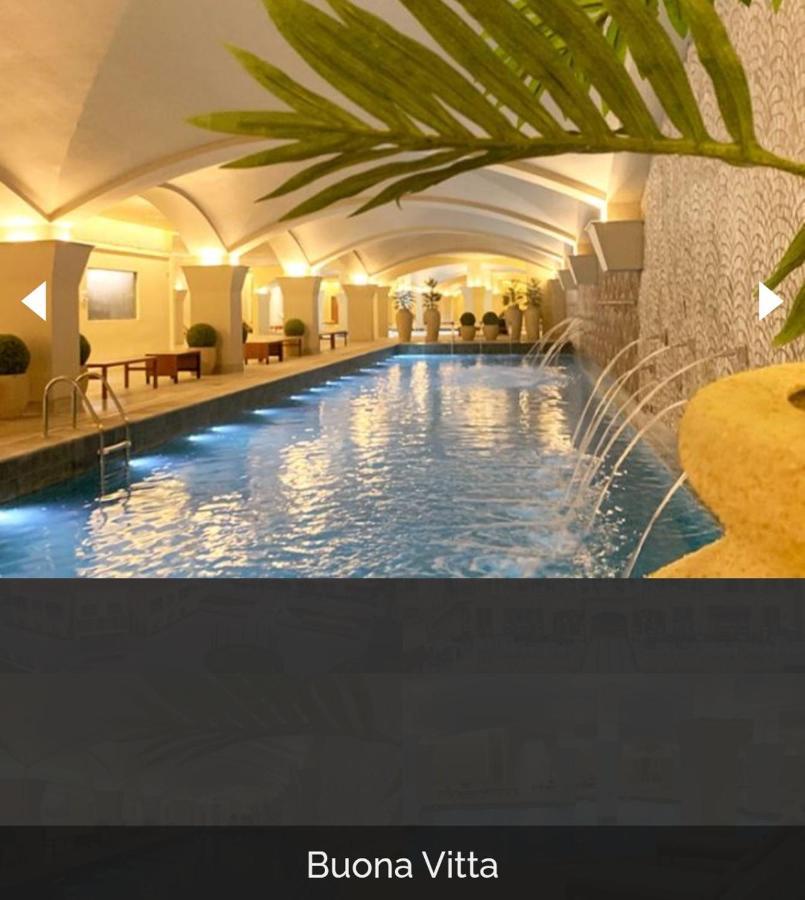 Hotel Buona Vitta Gramado by Gramado Parks Esterno foto The photo depicts an elegant indoor swimming pool area. The pool is illuminated with lights along its edge, and there are gentle water features creating a calming atmosphere. The ceiling has an arched design, and the space is decorated with plants an