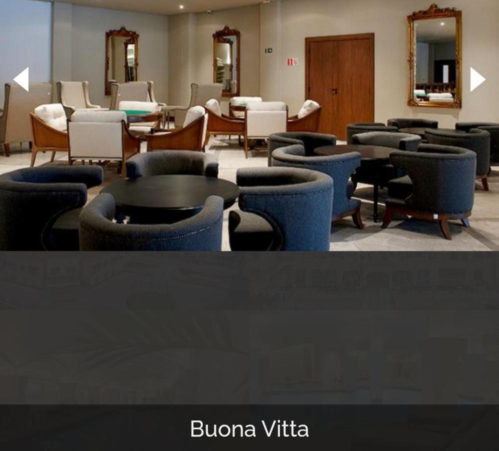 Hotel Buona Vitta Gramado by Gramado Parks Esterno foto The photo shows a modern, elegantly designed lounge or waiting area. It features several circular seating arrangements with dark blue armchairs surrounding black tables. In the background, there are light-colored lounge chairs and a wooden door leadi