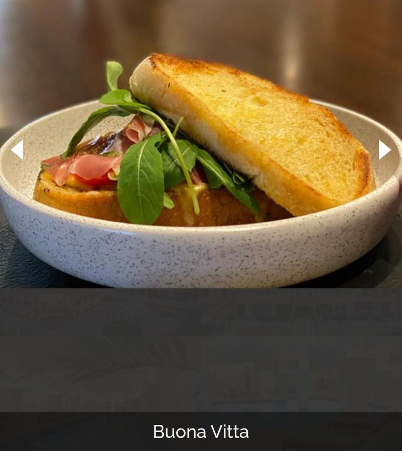 Hotel Buona Vitta Gramado by Gramado Parks Esterno foto The photo shows a dish presented in a round, speckled bowl. It features a slice of toasted bread resting on top of a combination of ingredients beneath. The ingredients include leafy greens and slices of what appears to be cured meat, possibly ham. T