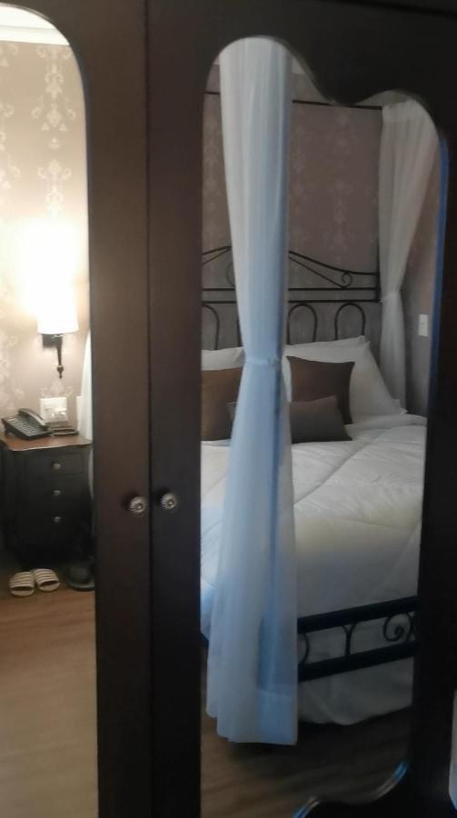 Hotel Buona Vitta Gramado by Gramado Parks Esterno foto The photo shows a cozy bedroom scene. It features a bed with white bedding and several brown accent pillows. The bed is framed by a decorative headboard and appears to be situated against a wall with subtle patterns. Next to the bed, there is a night