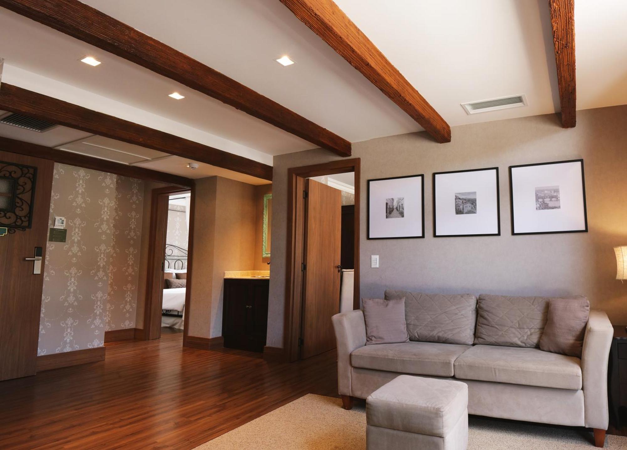 Hotel Buona Vitta Gramado by Gramado Parks Esterno foto The photo showcases a modern living space with a cozy and well-lit atmosphere. There are wooden beams visible on the ceiling, adding a rustic touch. The flooring is a warm-toned wood, contributing to the inviting feel of the room. 

On one side, ther